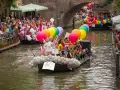 Dzień kobiet w Holandii świętowany na wodnej paradzie. Łodzie pełne kolorowych balonów i ludzi w tęczowych barwach.