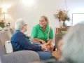 Uśmiechnięta opiekunka rozmawia z seniorką. Szukasz ofert pracy w Venray?