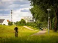 Rowerzysta w parku w Venlo, w tle wieża kościelna i nowoczesny budynek.