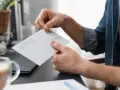 Mężczyzna przykleja znaczek na kopercie, przygotowując się do wysłania listu w Holandii.