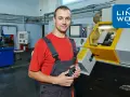 Pracownik w warsztacie w Rotterdamie, gotowy do pracy przy maszynie CNC. Logo Link2Work.