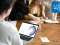 Zespół pracuje nad projektem, analizując dane na laptopie. To idealne miejsce, by zacząć pracę zdalną bez doświadczenia i rozwijać się z Link2Work.