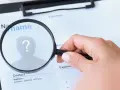 Dłoń z lupą bada CV, szukając idealnego kandydata. Techvisie Deventer w akcji!
