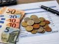 Euro banknoty i monety na dokumencie z danymi finansowymi. Planowanie budżetu na remonty w Holandii.