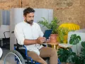 Mężczyzna na wózku inwalidzkim przegląda tablet, szukając informacji o rencie chorobowej w Holandii.