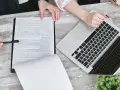 Dwie osoby przy biurku analizują dokumenty i laptopa. Planują swoją **pracę w Holandii**.