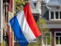 Holenderska flaga powiewa przed domami, które mogą wpływać na ceny domów w Holandii.