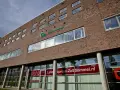 Nowoczesny budynek z cegły z logo AB Midden Nederland. Na parterze szyld "Lunch express-Zaltbommel.nl".