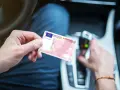 Polak trzyma polskie prawo jazdy w samochodzie. Dokument jest ważny w całej Unii Europejskiej, w tym w Holandii.