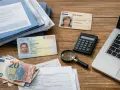 Dokumenty, pieniądze i kalkulator na biurku. Widoczny jest Sofi-kaart, dowód osobisty, euro i formularze, które mogą być związane z numerem podatkowym Holandia.