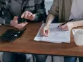 Para rozlicza się z hollandzorg, planując zwrot ubezpieczenia. Kalkulator i telefon pomagają w wypełnianiu dokumentów.