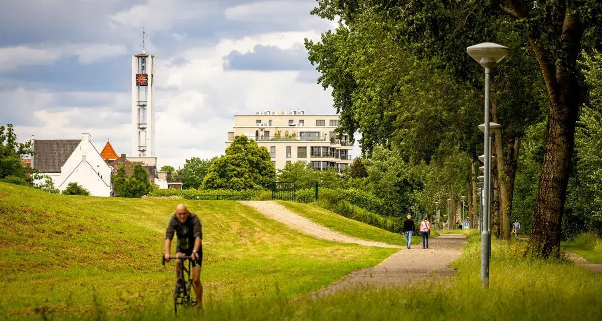 Rowerzysta w parku w Venlo, w tle wieża kościelna i nowoczesny budynek.