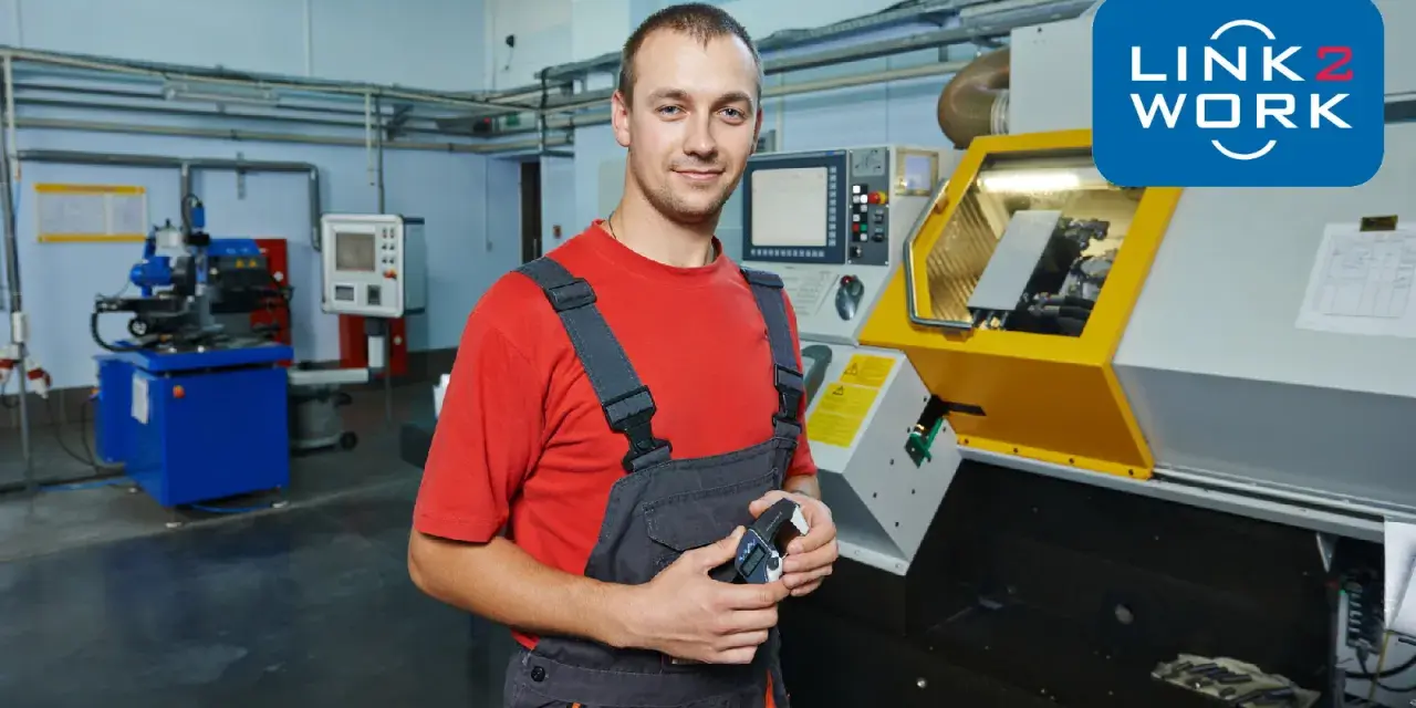 Pracownik w warsztacie w Rotterdamie, gotowy do pracy przy maszynie CNC. Logo Link2Work.