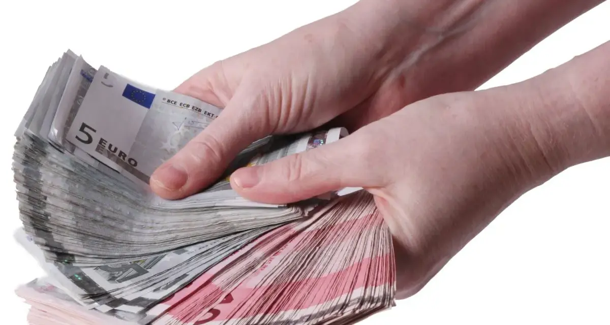 Twee handen tellen een stapel eurobiljetten, waaronder 5 euro biljetten. Een stapel geld, een stipp hollandia.