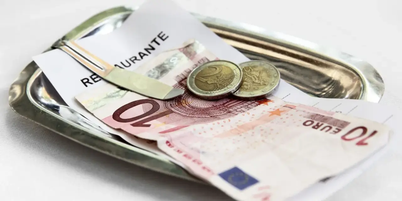 Na tacy leżą rachunek, banknot 10 euro i dwie monety. Tak wyglądają napiwki w Holandii.