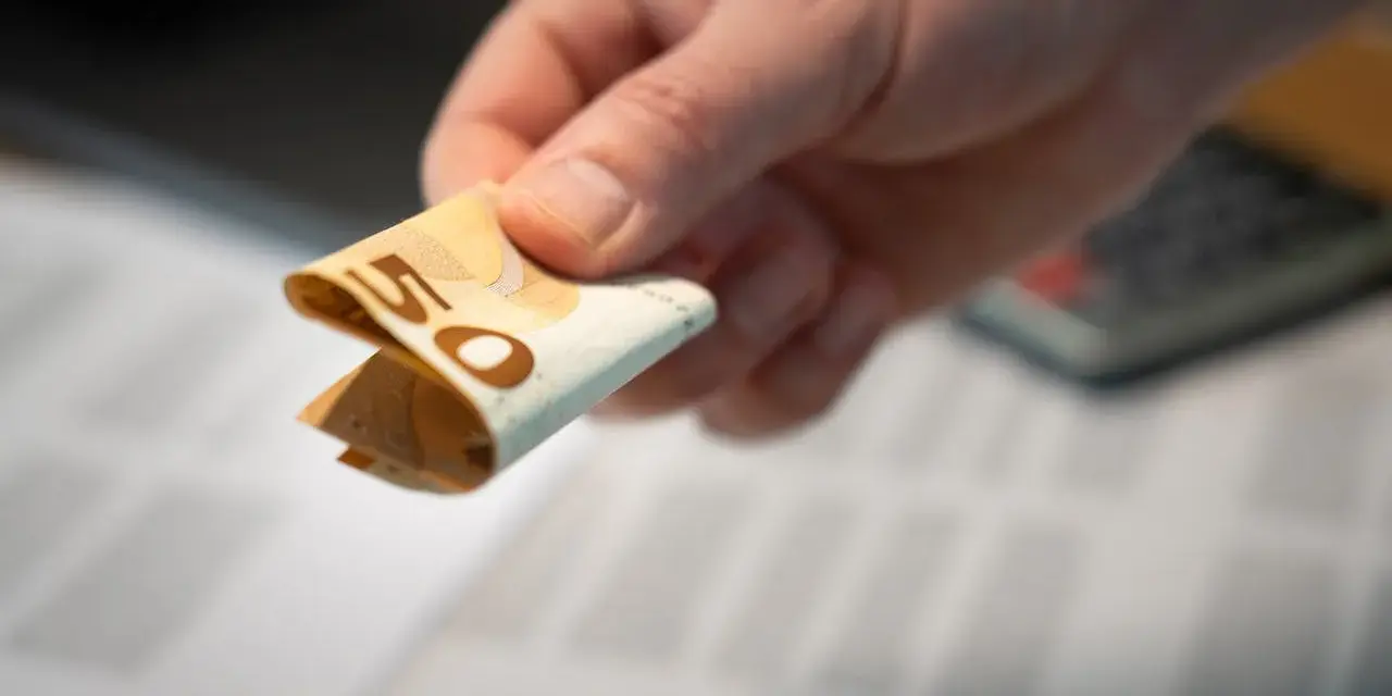Dłoń trzyma złożoną pięćdziesięcioeuro banknot. Może to być zwrot zorgtoeslag.