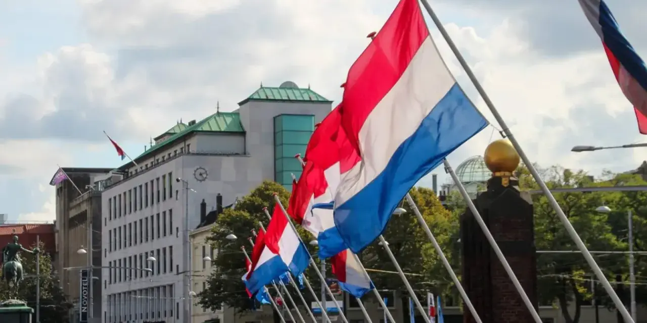 Holandia świętuje! Rząd flag narodowych powiewa na wietrze przed nowoczesnym budynkiem.