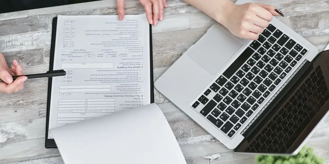 Dwie osoby przy biurku analizują dokumenty i laptopa. Planują swoją **pracę w Holandii**.