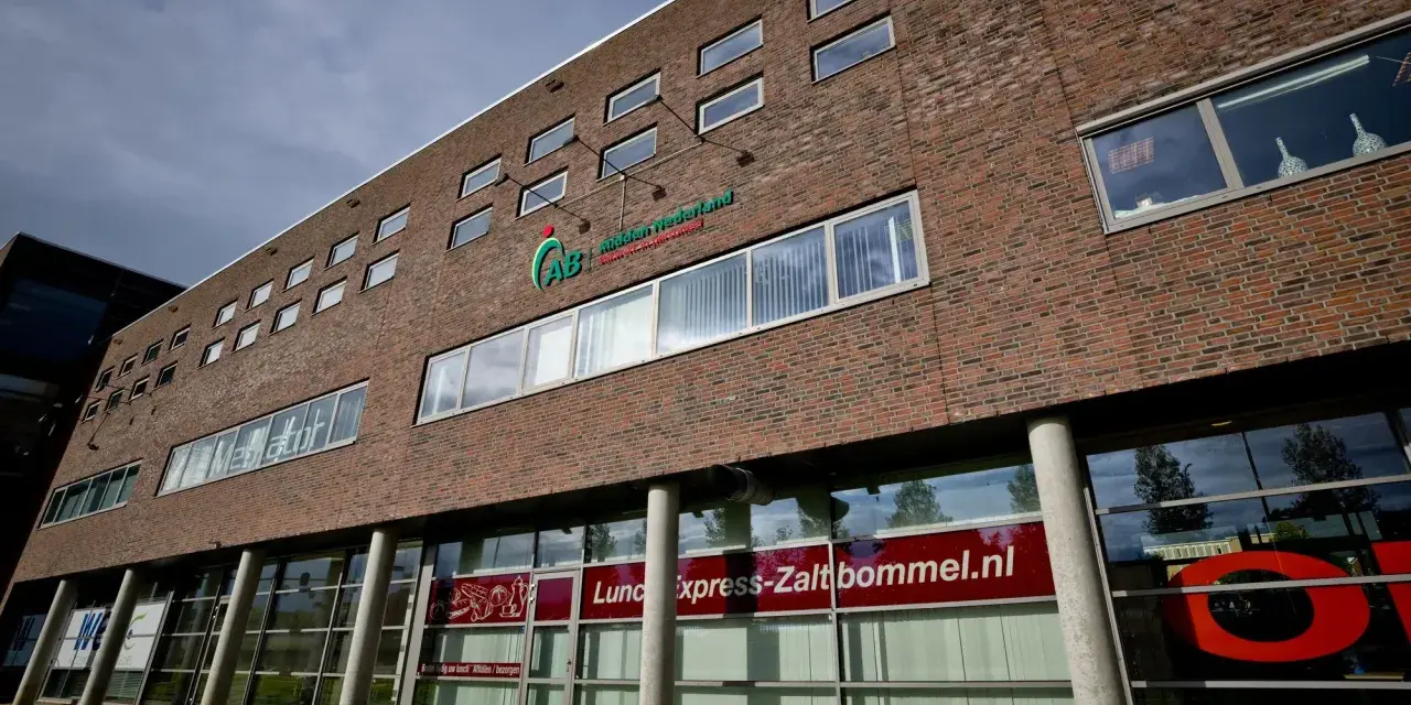 Nowoczesny budynek z cegły z logo AB Midden Nederland. Na parterze szyld "Lunch express-Zaltbommel.nl".