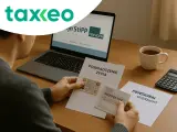 Mężczyzna sprawdza dokumenty, by dowiedzieć się, jak wypłacić pieniądze ze Stipp. Na biurku laptop, dokumenty i kubek kawy.