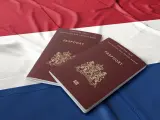 Dwa holenderskie paszporty na tle flagi Holandii. Dokumenty te mogą być kluczem do nowego życia dla wielu Polaków.