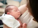 Śpiące polskie dziecko urodzone w Holandii, otulone białym kocykiem, w ramionach mamy.