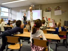 Dzieci na lekcji w Holandii, z podniesionymi rękami. Dowiedz się, jak zapisać dziecko do szkoły w Holandii.
