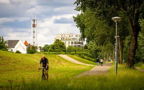 Rowerzysta w parku w Venlo, w tle wieża kościelna i nowoczesny budynek.