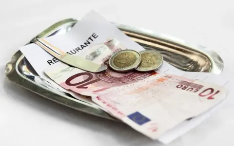 Na tacy leżą rachunek, banknot 10 euro i dwie monety. Tak wyglądają napiwki w Holandii.