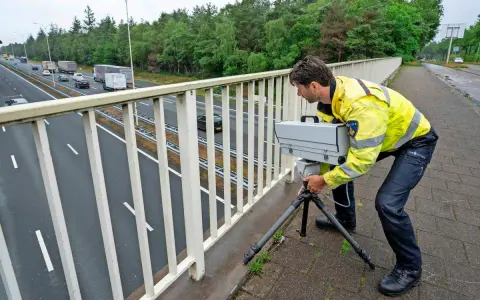 Policjant w Holandii ustawia radar na moście, by egzekwować przepisy drogowe.