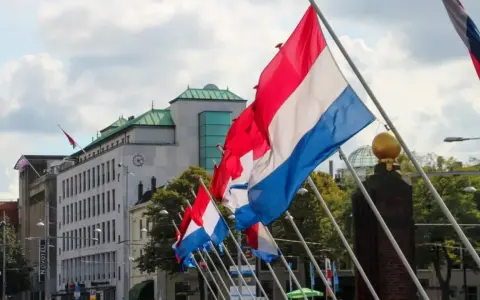 Holandia świętuje! Rząd flag narodowych powiewa na wietrze przed nowoczesnym budynkiem.