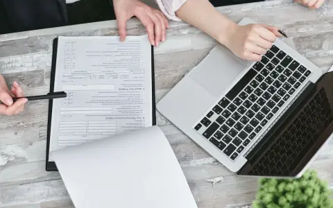 Dwie osoby przy biurku analizują dokumenty i laptopa. Planują swoją **pracę w Holandii**.