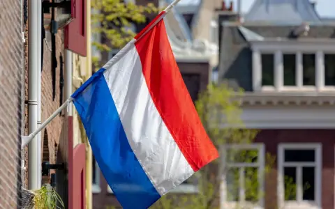 Holenderska flaga powiewa przed domami, które mogą wpływać na ceny domów w Holandii.