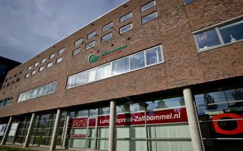 Nowoczesny budynek z cegły z logo AB Midden Nederland. Na parterze szyld "Lunch express-Zaltbommel.nl".