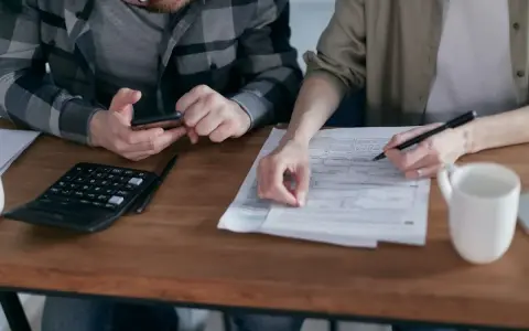 Para rozlicza PIT. Na stole kalkulator, telefon i dokumenty.