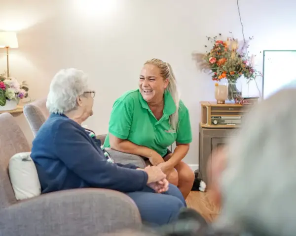 Uśmiechnięta opiekunka rozmawia z seniorką. Szukasz ofert pracy w Venray?