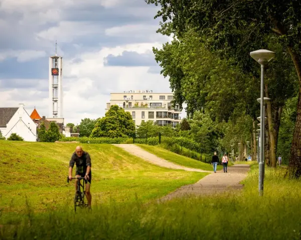 Rowerzysta w parku w Venlo, w tle wieża kościelna i nowoczesny budynek.