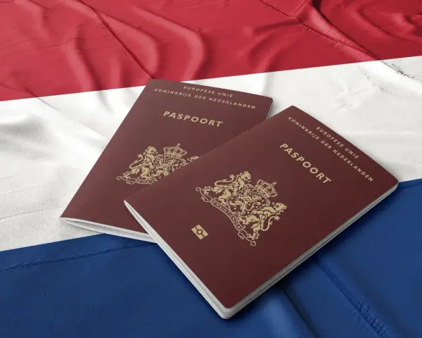 Dwa holenderskie paszporty na tle flagi Holandii. Dokumenty te mogą być kluczem do nowego życia dla wielu Polaków.
