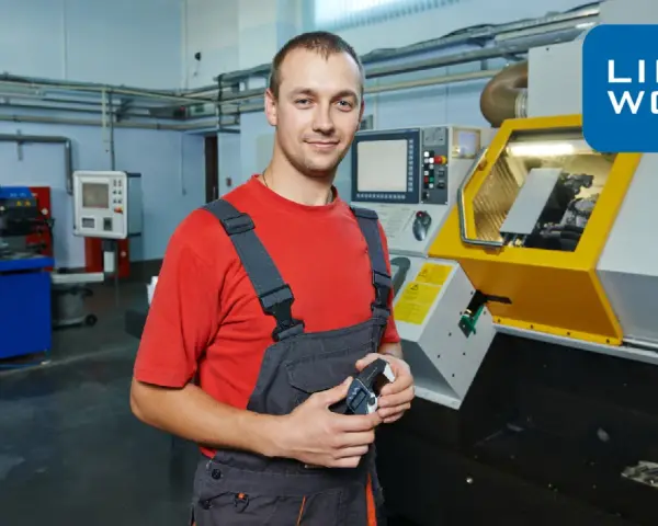 Pracownik w warsztacie w Rotterdamie, gotowy do pracy przy maszynie CNC. Logo Link2Work.