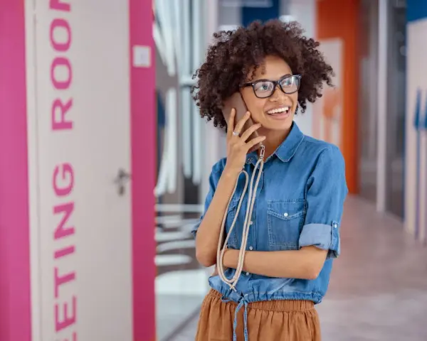 Vrolijke vrouw met bril belt op, mogelijk een recruiter in Nederland die een nieuwe baan regelt.