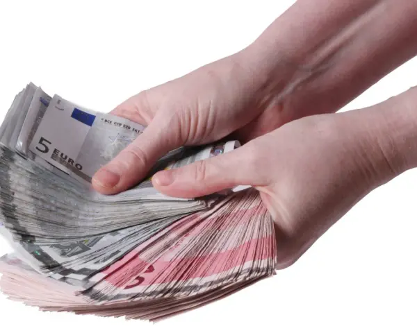 Twee handen tellen een stapel eurobiljetten, waaronder 5 euro biljetten. Een stapel geld, een stipp hollandia.