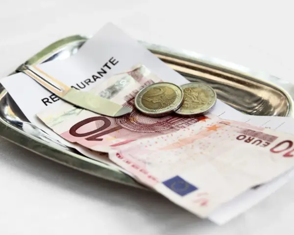 Na tacy leżą rachunek, banknot 10 euro i dwie monety. Tak wyglądają napiwki w Holandii.
