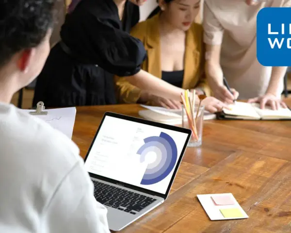 Zespół pracuje nad projektem, analizując dane na laptopie. To idealne miejsce, by zacząć pracę zdalną bez doświadczenia i rozwijać się z Link2Work.