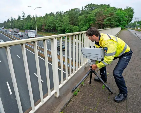 Policjant w Holandii ustawia radar na moście, by egzekwować przepisy drogowe.