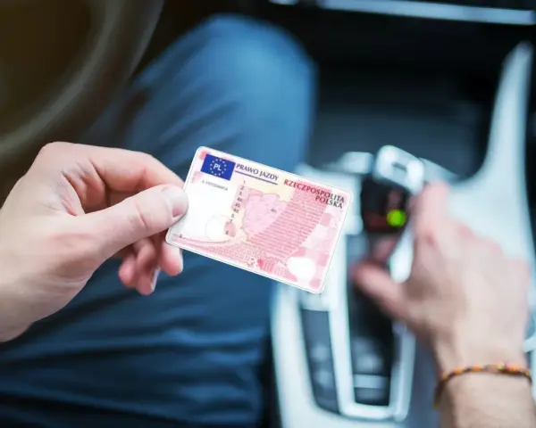 Polak trzyma polskie prawo jazdy w samochodzie. Dokument jest ważny w całej Unii Europejskiej, w tym w Holandii.