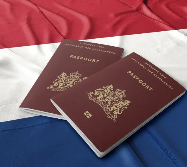 Dwa holenderskie paszporty na tle flagi Holandii. Dokumenty te mogą być kluczem do nowego życia dla wielu Polaków.