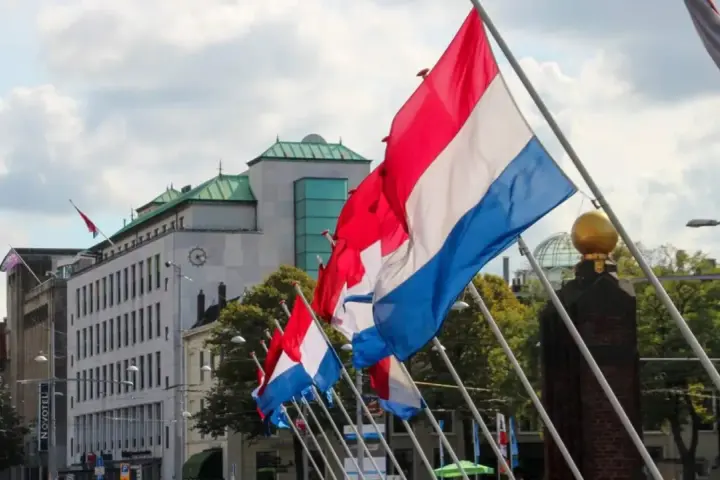 Holandia świętuje! Rząd flag narodowych powiewa na wietrze przed nowoczesnym budynkiem.
