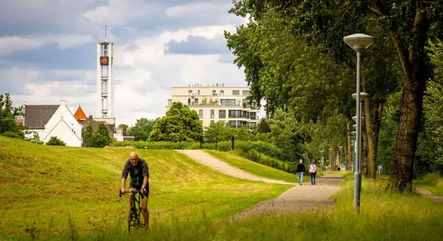Rowerzysta w parku w Venlo, w tle wieża kościelna i nowoczesny budynek.