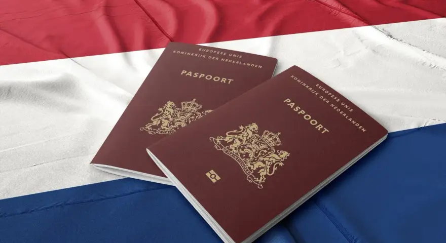 Dwa holenderskie paszporty na tle flagi Holandii. Dokumenty te mogą być kluczem do nowego życia dla wielu Polaków.