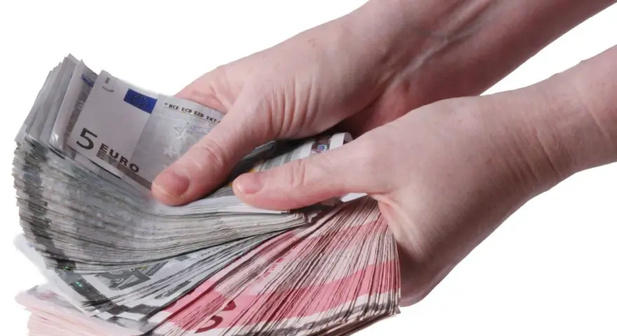 Twee handen tellen een stapel eurobiljetten, waaronder 5 euro biljetten. Een stapel geld, een stipp hollandia.
